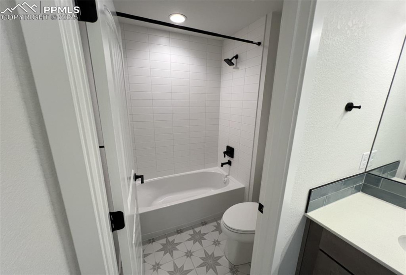 Full bathroom featuring a textured wall, vanity, and shower / bath combination