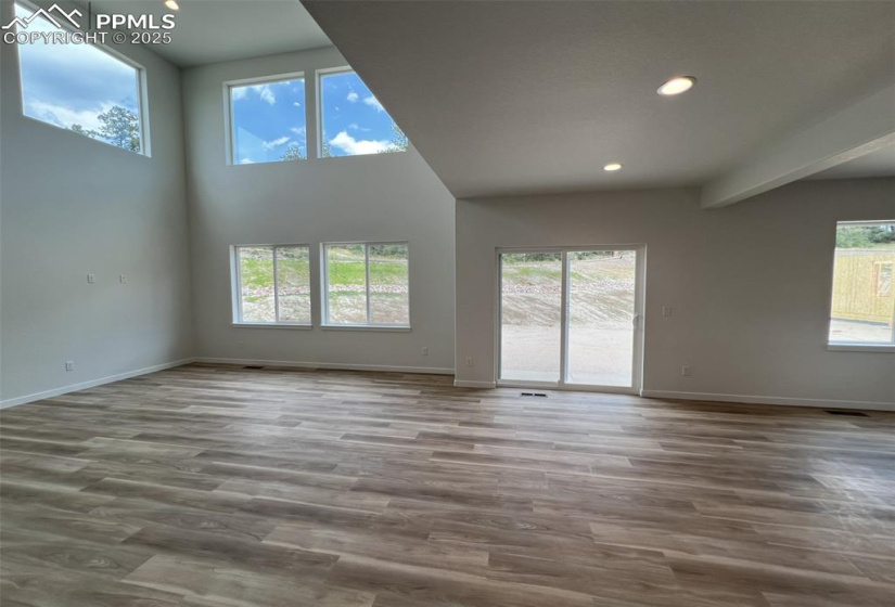 Unfurnished living room featuring recessed lighting, light wood-style flooring, and a towering ceiling
