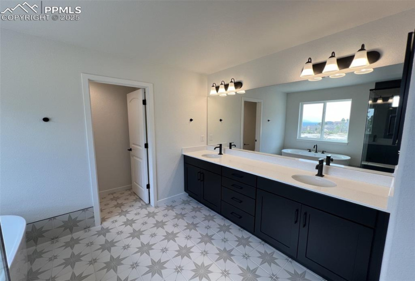 Bathroom featuring a soaking tub, double vanity, and light floors