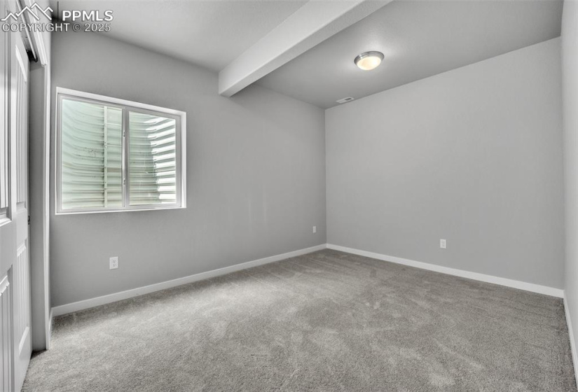 Carpeted spare room featuring beamed ceiling and baseboards