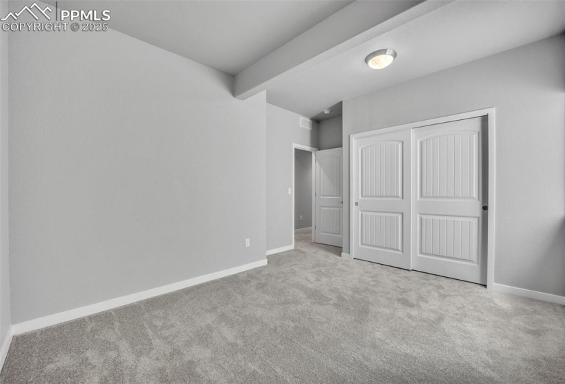 Unfurnished bedroom with carpet floors, a closet, baseboards, and beamed ceiling